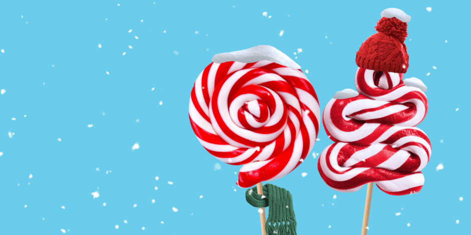 Snow falls against a light blue background. On the right are two large red and white swirled lolly pops. One is round and has green tinsel on its stick. The other is shaped like a Christmas tree and is wearing a small red woolly hat.